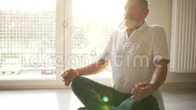 <strong>瑜伽课程</strong>。 修行，一位年长的<strong>瑜伽</strong>士坐在地板上的莲花位置。 阳光照射